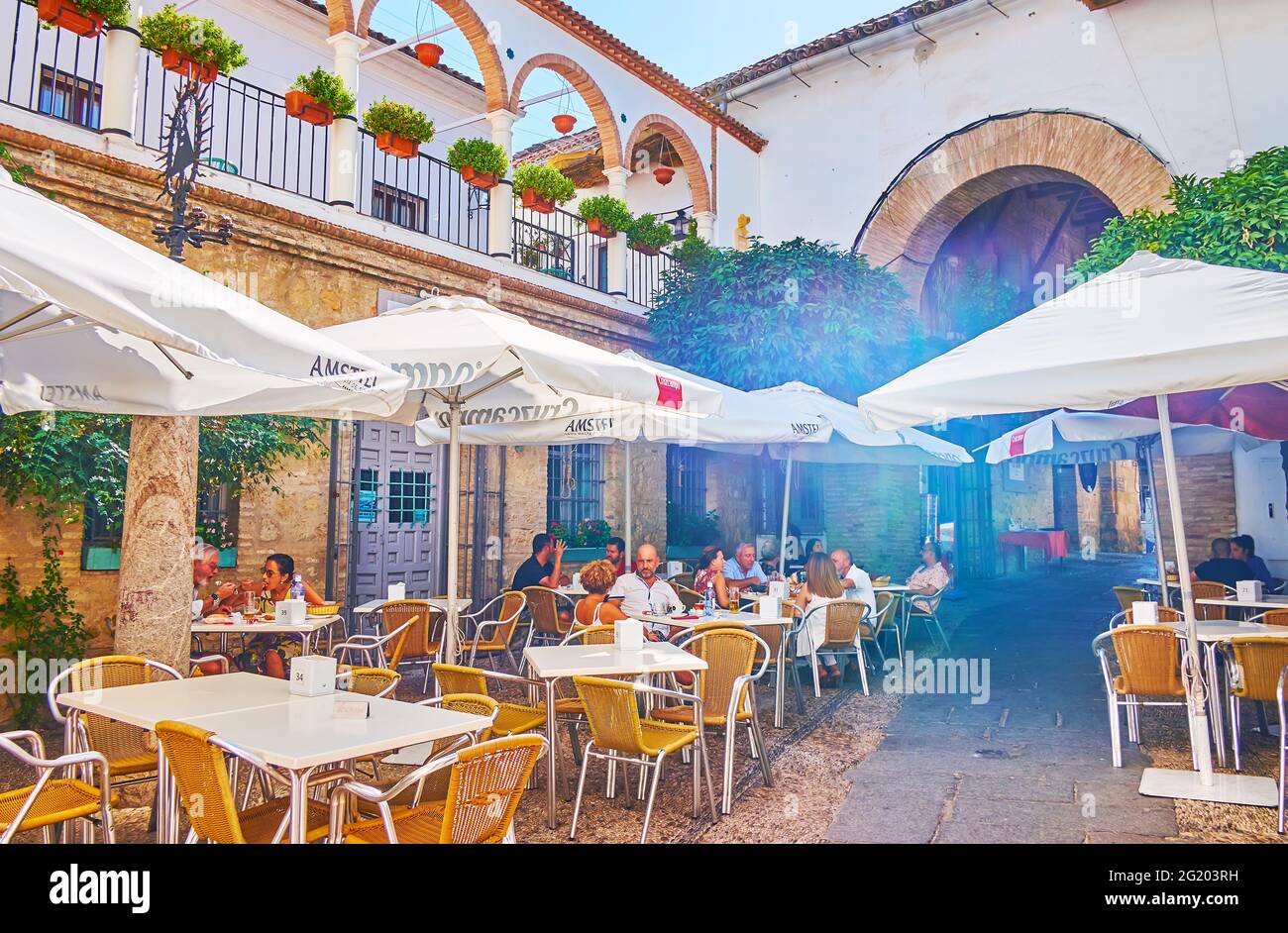CORDOVA, SPAGNA - 30 SETTEMBRE 2019: La stretta strada Calleja de la Luna con tavoli e ombrelloni di ristorante all'aperto, vicino con una porta del Mo Foto Stock