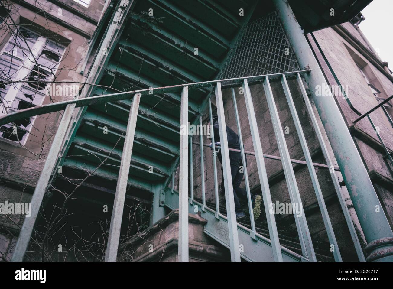 Esplorazione urbana - salire su una scala in metallo in un edificio abbandonato all'aperto Foto Stock