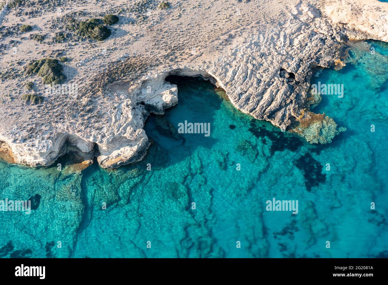 Grecia. CICLADI. Seascape con grotte e rocce su verde acqua di mare trasparente smeraldo, piccola isola delle Cicladi, drone aereo vista dall'alto verso il basso Foto Stock