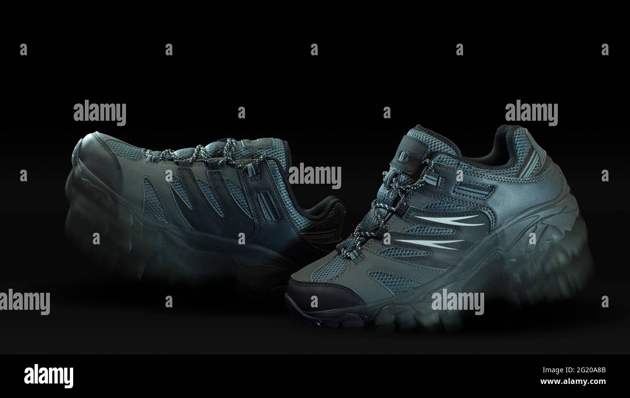 Primo piano su un paio di scarpe sportive in tessuto grigio blu e pelle una di fronte all'altra con effetto camminante su sfondo nero Foto Stock