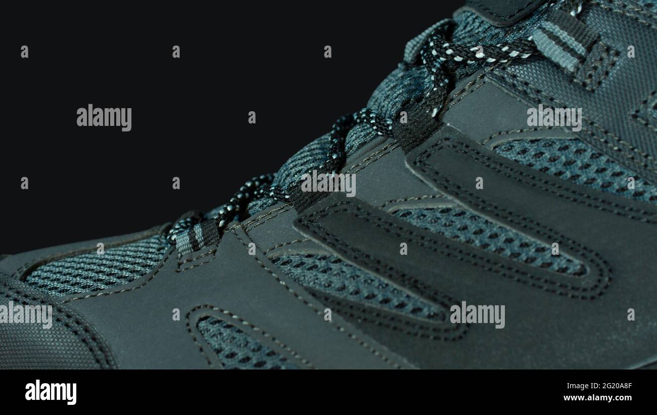 Primo piano sulla parte superiore di un tessuto grigio blu e scarpe sportive in pelle su sfondo nero Foto Stock