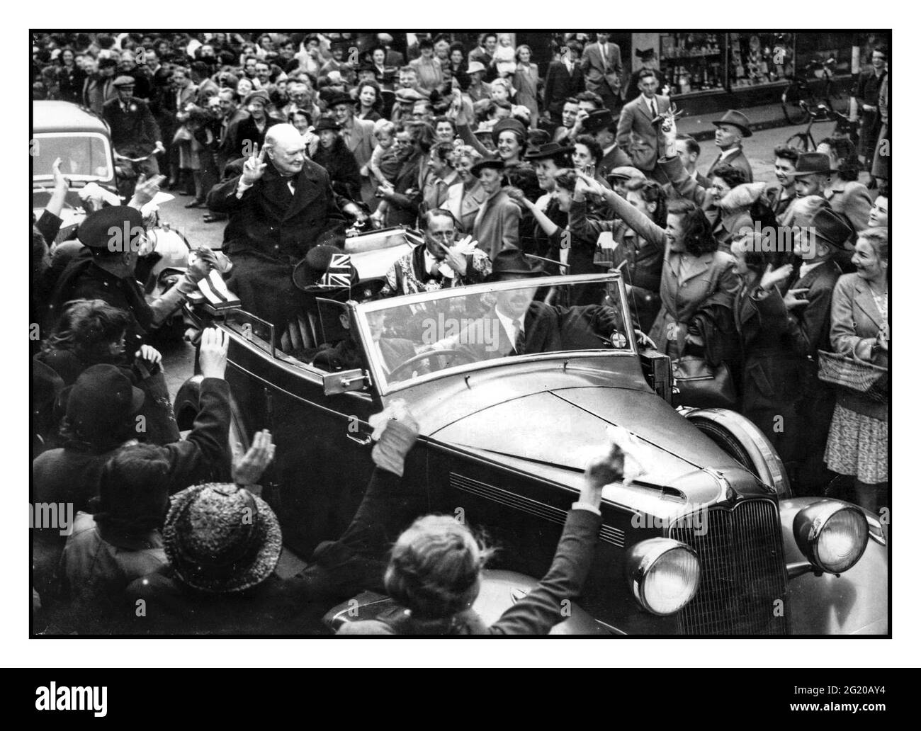 Winston Churchill dà il segno della vittoria mentre la sua auto guida lentamente attraverso la folla di tifosi in Queen Street dopo la cerimonia della libertà al Municipio di Cardiff. 16 luglio 1948. Foto Stock