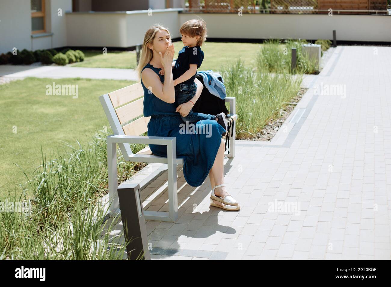 Madre single a piedi si siede sulla panchina con il suo figlio di 3 anni in braccio. Concetto di intimità e amore per i bambini Foto Stock