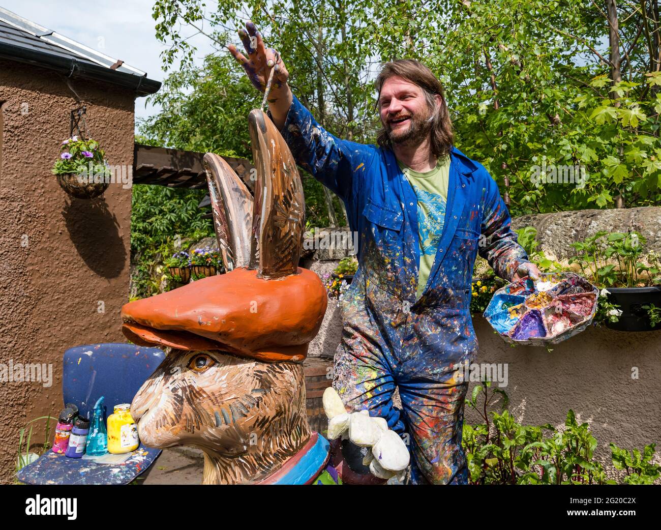 L'artista Chris Rutterford dipinge una gigantesca scultura di lepre in fibra di vetro nel suo studio all'aperto per un percorso artistico di beneficenza, in Scozia, Regno Unito Foto Stock