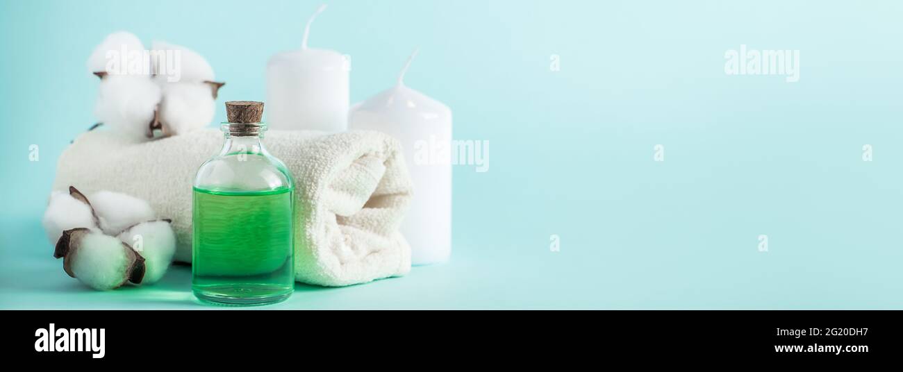 Prodotti naturali biologici di bellezza per spa e aromaterapia. Olio essenziale aromatico, candele e un asciugamano su sfondo blu. Concetto di relax, luogo Foto Stock