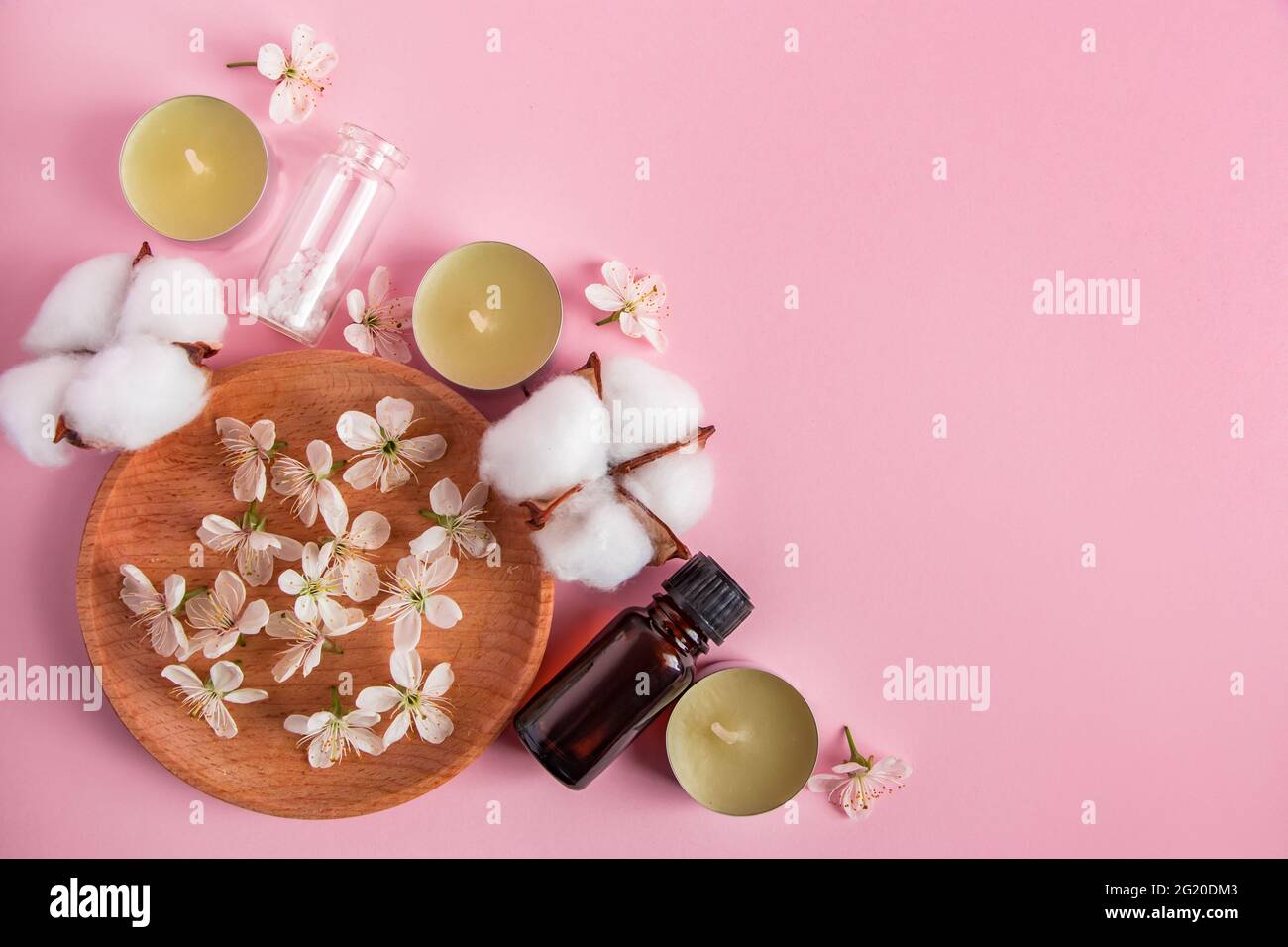 Cura della pelle, spa e concetto di aromaterapia. Prodotti cosmetici naturali su sfondo rosa. Aroma candele e fiori per relax e yoga. Luogo per Foto Stock