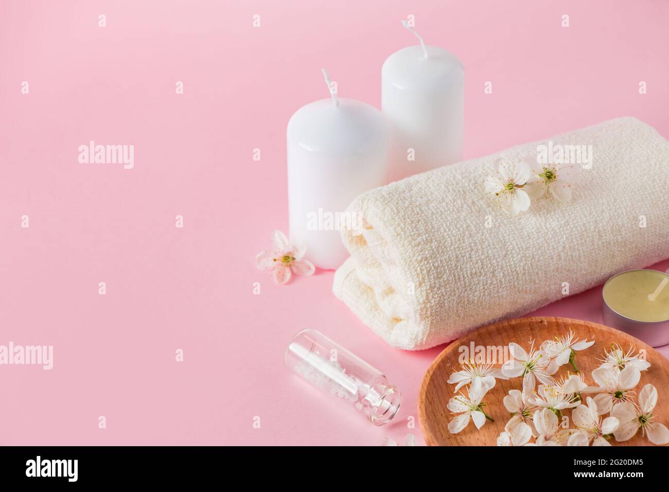 Prodotti cosmetici naturali per spa e aromaterapia. Concetto di relax. Candele, fiori e un asciugamano su sfondo rosa. Inserire il testo. Foto Stock