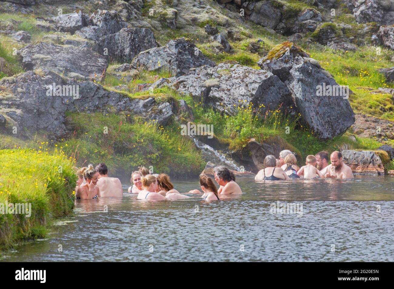 I turisti che nuotano nelle terme calde nella valle di Landmannalaugar, nella riserva naturale di Fjallabak, nel parco naturale vicino a Hekla / Hecla in estate, Sudurland, Islanda Foto Stock
