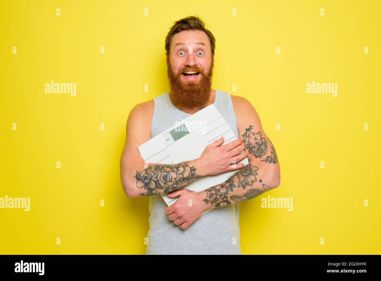 L'uomo felice con la barba e i tatuaggi ha un equilibrio elettronico Foto Stock