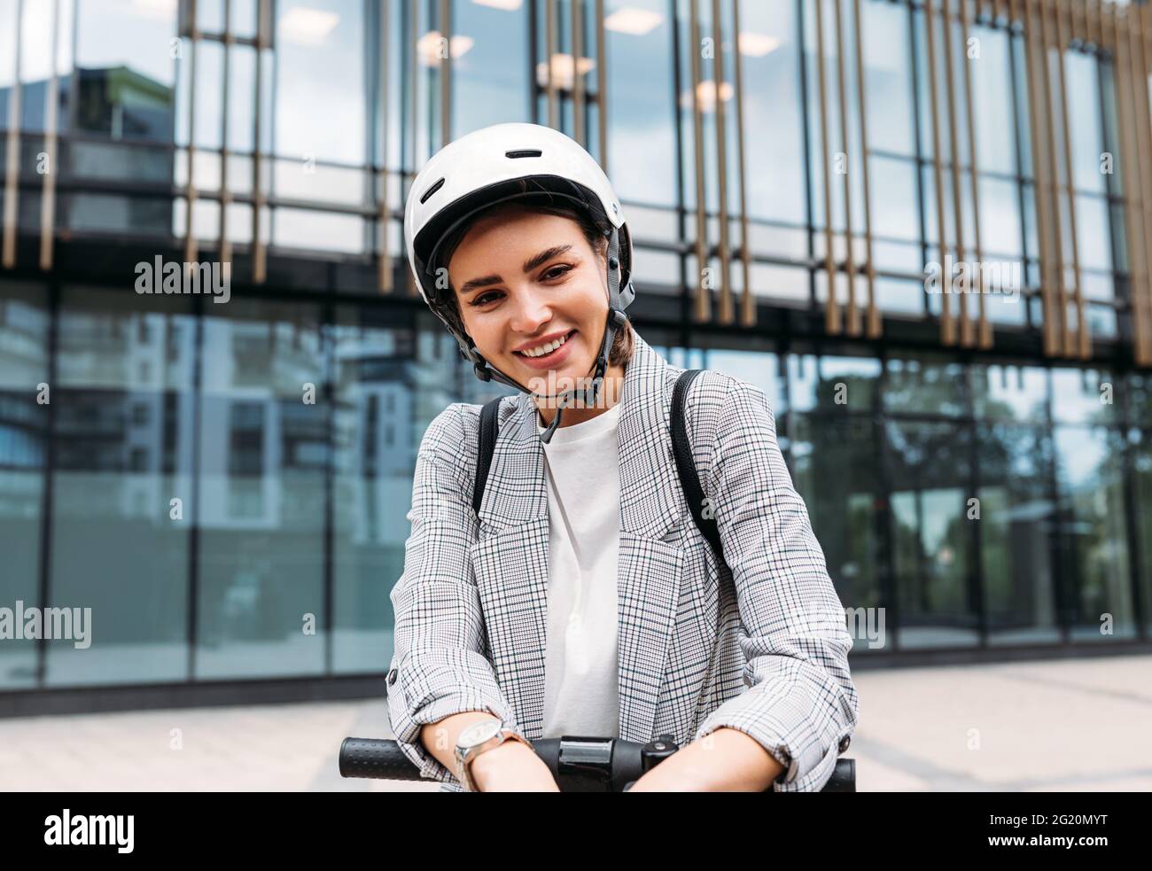 Ritratto di una donna allegra con casco di sicurezza sulla testa in piedi contro l'edificio Foto Stock