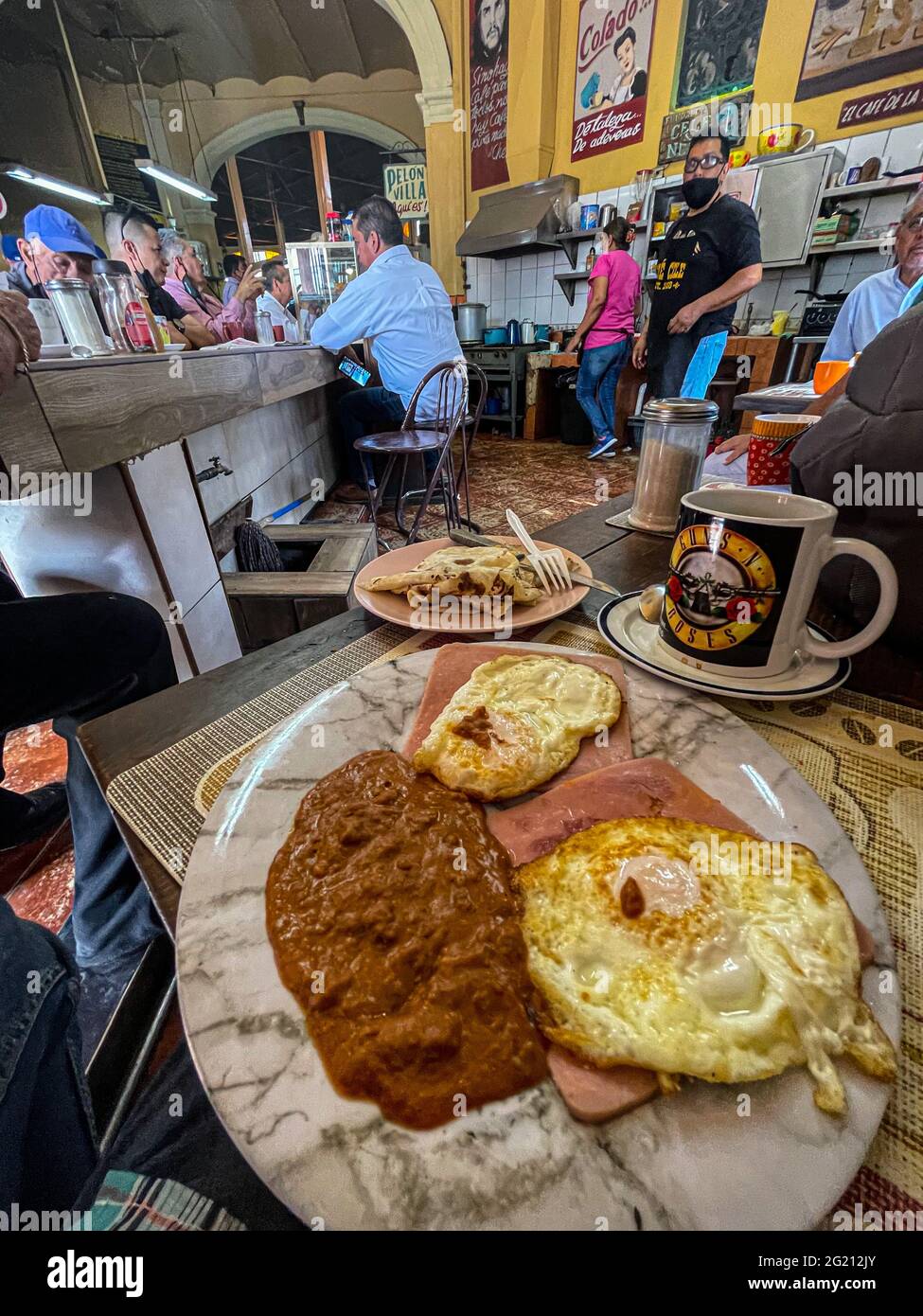Due uova strapazzate su fette di prosciutto, fagioli e caffè americano in una tazza Guns and Roses al Cafe Cele nel mercato municipale di Hermosillo, Messico. Colazione, cibo, cibo, pasti, cibo. (Foto di Luis Gutierrez / Norte Photo) Dos huevos estrellados sobre rebanadas de jamon, frijoles y cafe americano en tasa de Guns and Roses en el Cafe Cele del mercado Municipal de Hermosillo, Messico. Desayuno, Alimentos, comida, Comidas, cibo. (Foto di Luis Gutierrez/ Norte Photo) Foto Stock