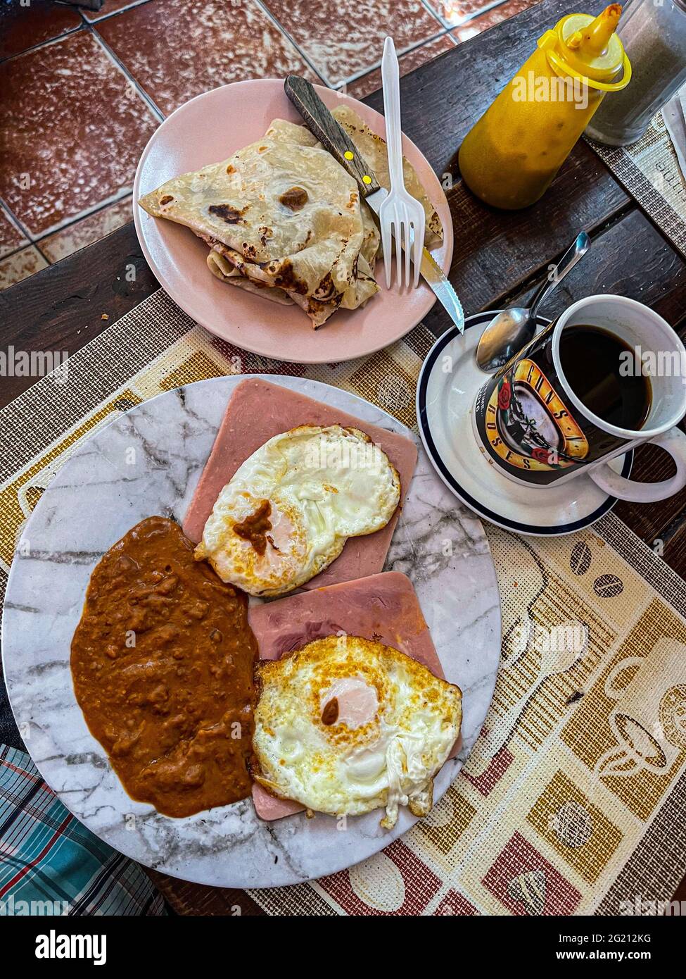Due uova strapazzate su fette di prosciutto, fagioli e caffè americano in una tazza Guns and Roses al Cafe Cele nel mercato municipale di Hermosillo, Messico. Colazione, cibo, cibo, pasti, cibo. (Foto di Luis Gutierrez / Norte Photo) Dos huevos estrellados sobre rebanadas de jamon, frijoles y cafe americano en tasa de Guns and Roses en el Cafe Cele del mercado Municipal de Hermosillo, Messico. Desayuno, Alimentos, comida, Comidas, cibo. (Foto di Luis Gutierrez/ Norte Photo) Foto Stock