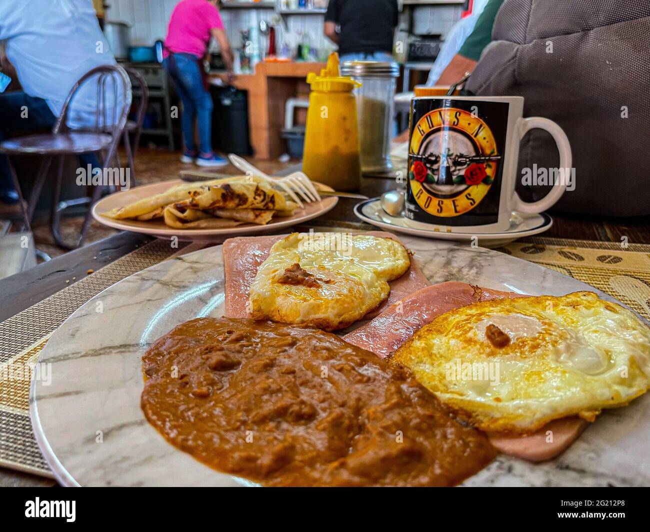 Due uova strapazzate su fette di prosciutto, fagioli, tortillas di farina e caffè americano in una tazza Guns and Roses al Cafe Cele nel mercato comunale di Hermosillo, Messico. Colazione, cibo, cibo, pasti, cibo. (Foto di Luis Gutierrez / Norte Photo) Dos huevos estrellados sobre rebanadas de jamon, frijoles, tortillas de harina y cafe americano en tasa de Guns and Roses en el Cafe Cele del mercado Municipal de Hermosillo, Messico. Desayuno, Alimentos, comida, Comidas, cibo. (Foto di Luis Gutierrez/ Norte Photo) Foto Stock