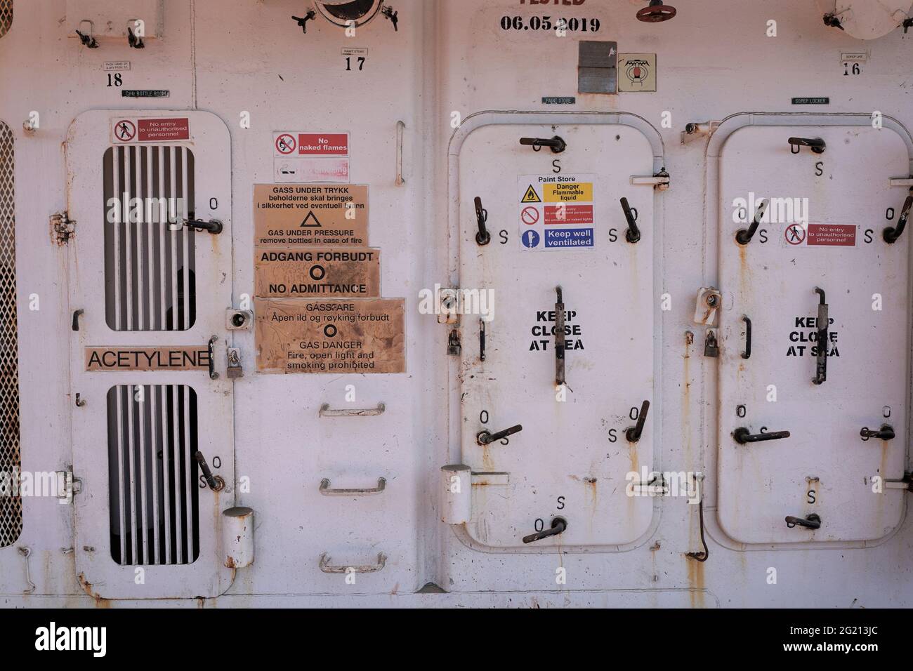 Insegne di sicurezza e sicurezza IMO sul lato della nave da carico che necessitano di manutenzione e verniciatura Foto Stock