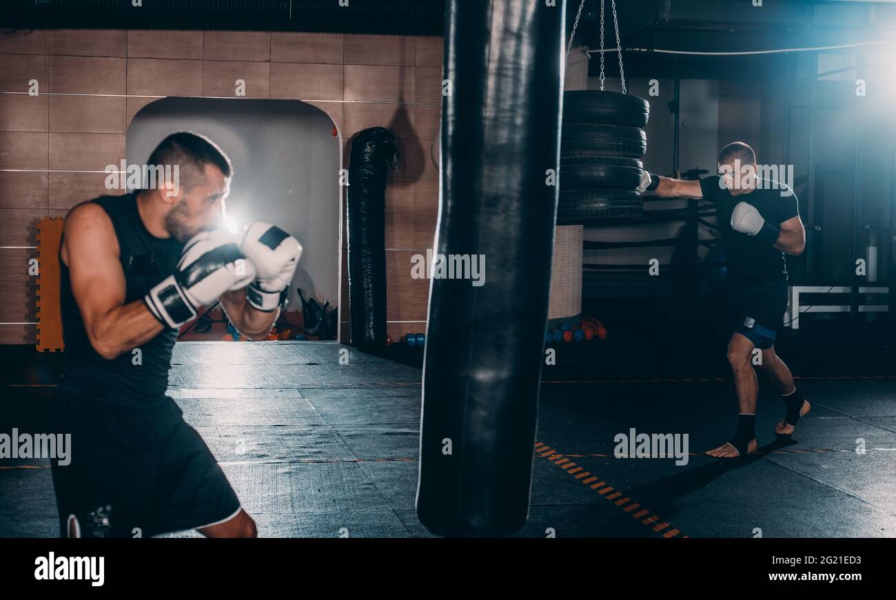 Giovane pugile muscolare utilizzando un sacco da boxe in palestra. Boxer di colpire la punzonatura Speed bag Foto Stock