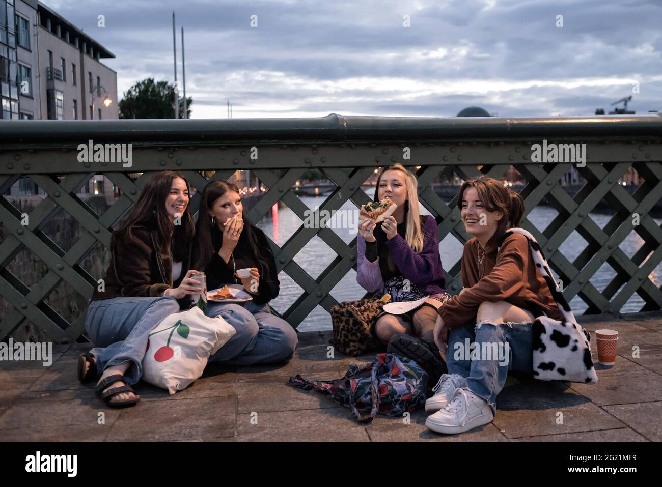 Le giovani donne hanno visto sedersi sul pavimento del Ponte di Grattan, mangiando pizze e conversando durante il fine settimana della festa della Banca. Dall'aprile 2021, Dublino ha gradualmente attenuato le restrizioni, e con la festa della banca in calo lunedì 7 giugno, il riscaldamento del tempo, e i servizi igienici pubblici installati nelle strade, diverse persone hanno scelto di trascorrere il fine settimana socializzando all'aperto nel centro della città. La grande folla ha provocato tensioni come le bottiglie che sono state gettate alla polizia, le persone che si rifiutano di trasferirsi quando la polizia li ha richiesti, e altri incidenti che hanno portato a 47 arresti fino ad oggi. (Pho Foto Stock