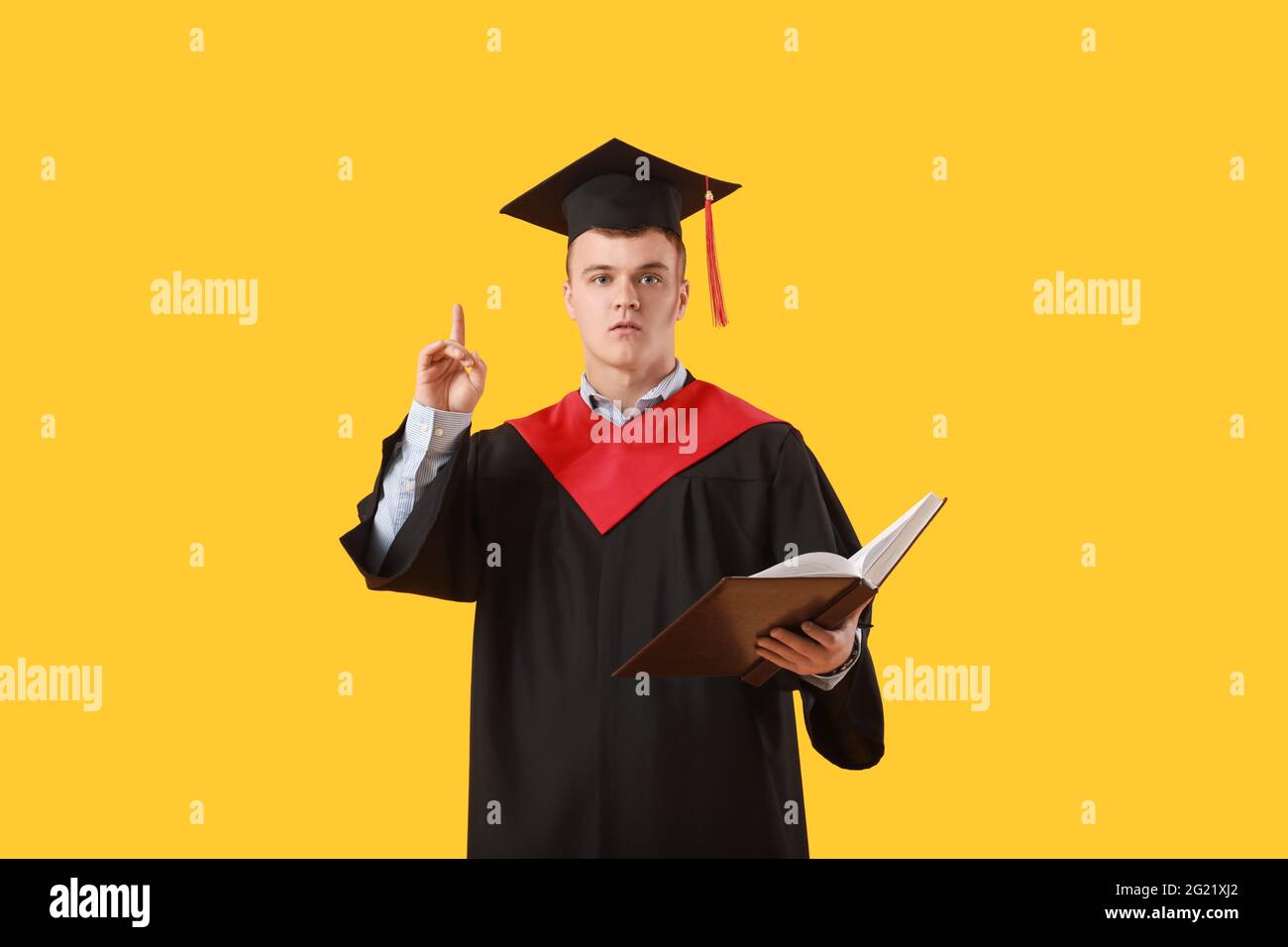 Studente di laurea maschile con indice rialzato su sfondo a colori Foto Stock