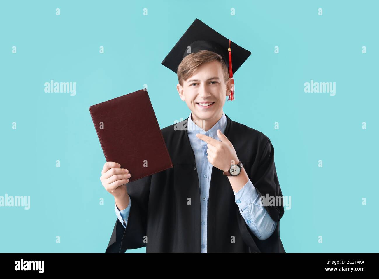 Studente di laurea maschile con libro su sfondo a colori Foto Stock