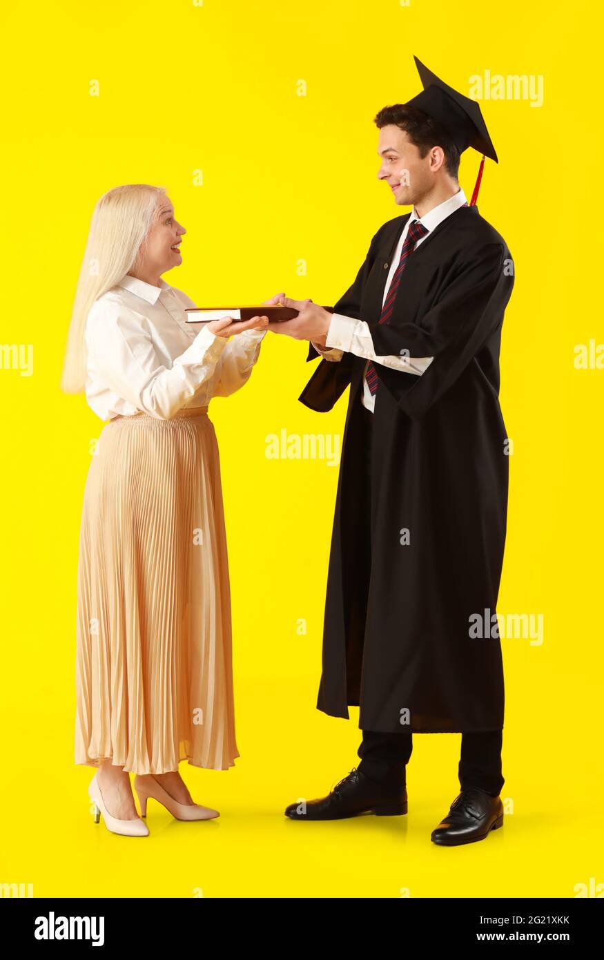 Felice studente di laurea maschile con sua madre su sfondo a colori Foto Stock