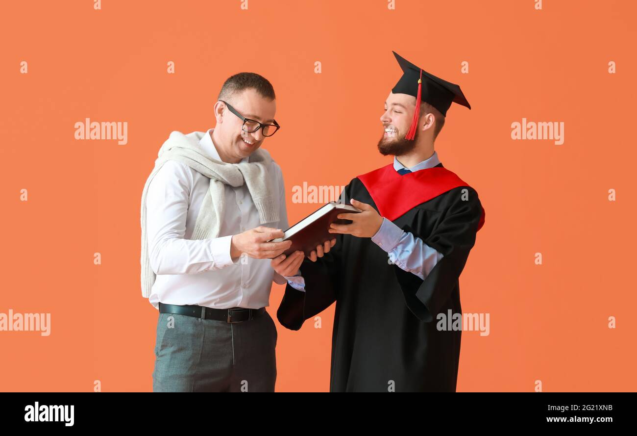 Felice studente di laurea maschile con suo padre su sfondo a colori Foto Stock