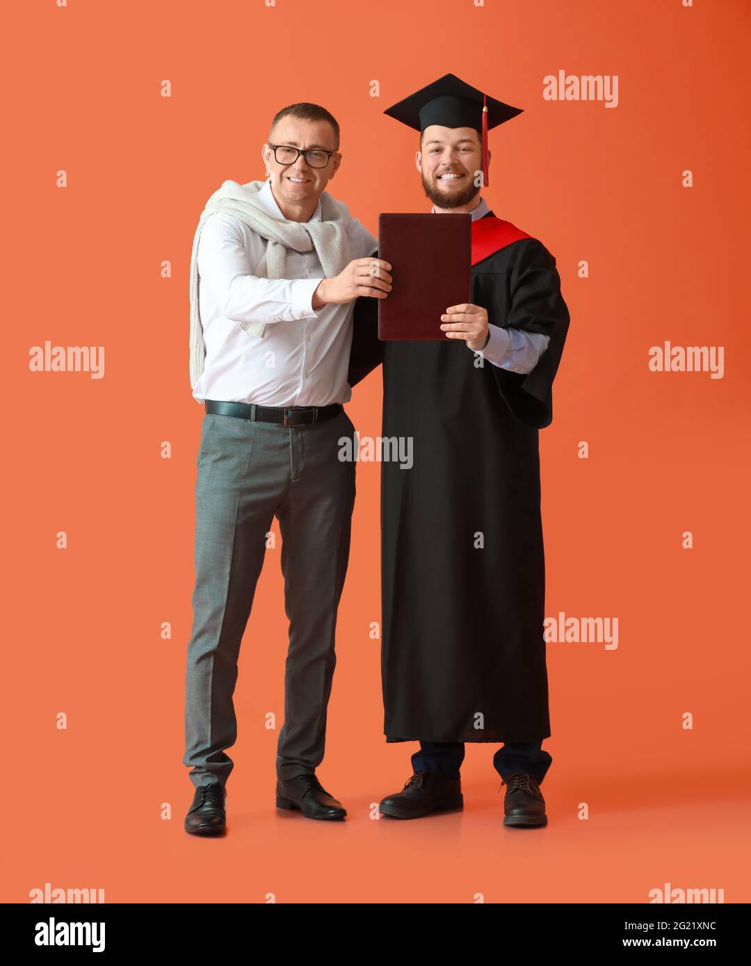 Felice studente di laurea maschile con suo padre su sfondo a colori Foto Stock