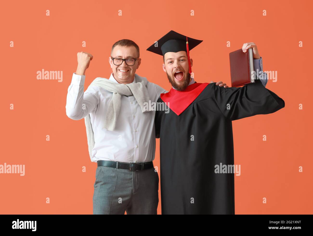 Felice studente di laurea maschile con suo padre su sfondo a colori Foto Stock