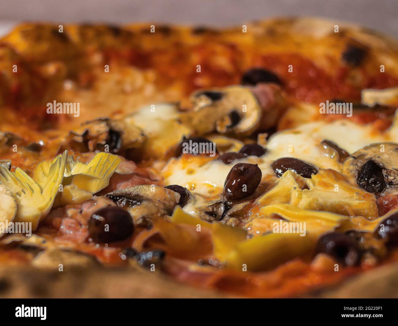 particolare di una pizza con pomodoro, mozzarella, funghi, olive e carciofi Foto Stock