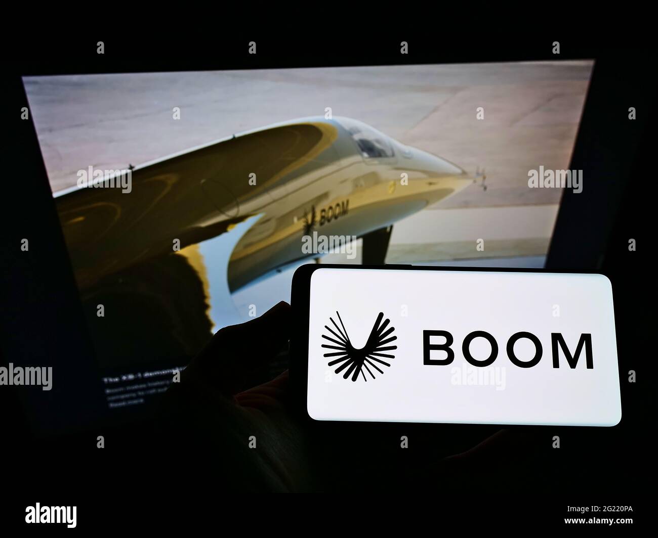 Persona che tiene il telefono mobile con il logo della società aerospaziale statunitense Boom Technology Inc (Supersonic) sullo schermo davanti alla pagina web. Mettere a fuoco il display del telefono. Foto Stock