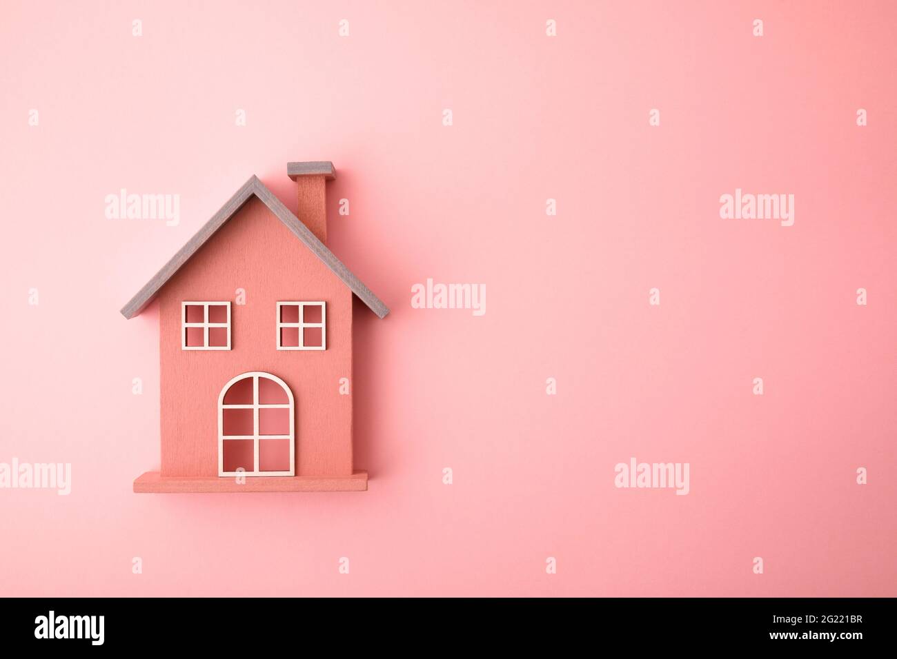 Piccola casa giocattolo di legno su sfondo rosa Foto Stock