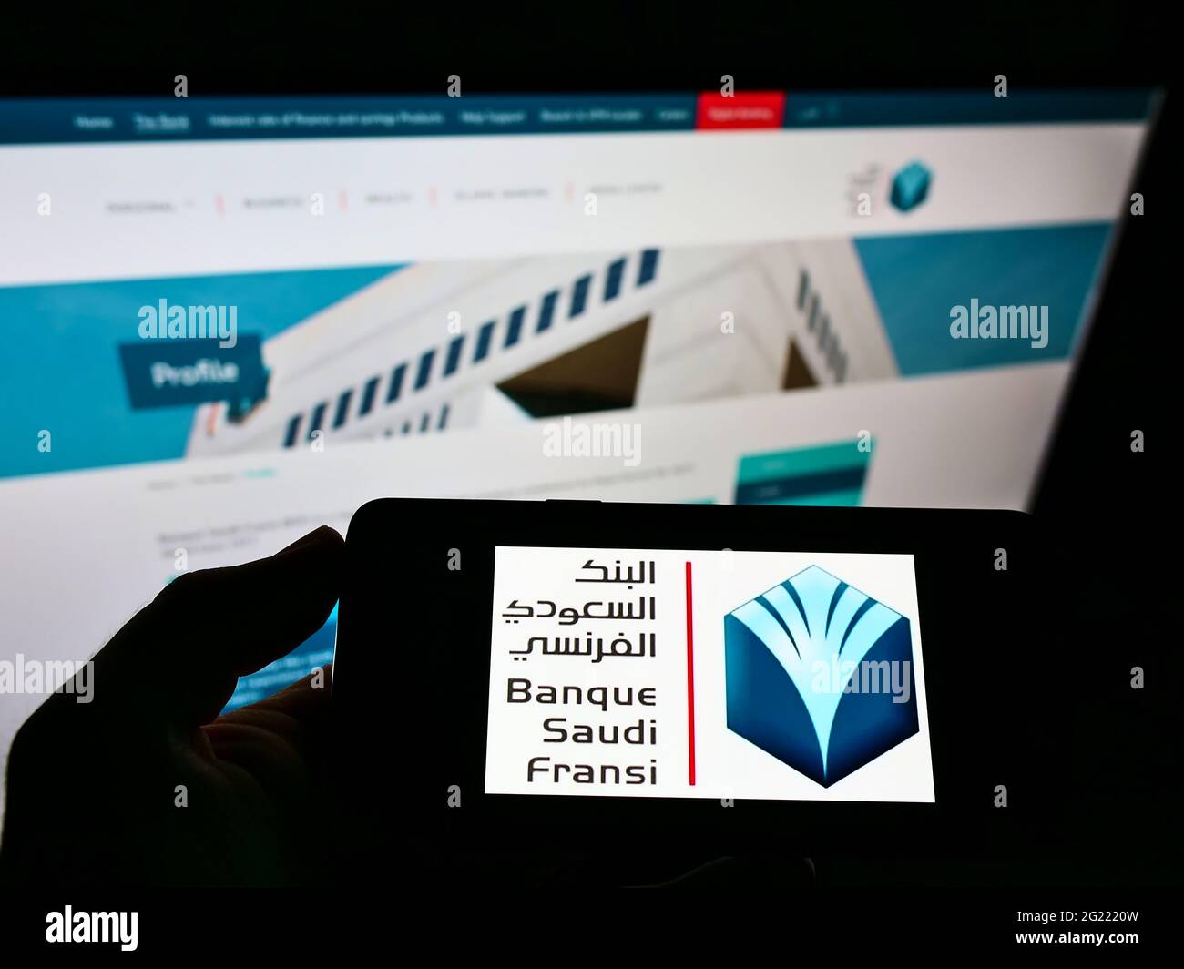 Persona in possesso di smartphone con logo della banca Saudita Banque Saudi Fransi (BSF) sullo schermo davanti al sito web. Mettere a fuoco il display del telefono. Foto Stock