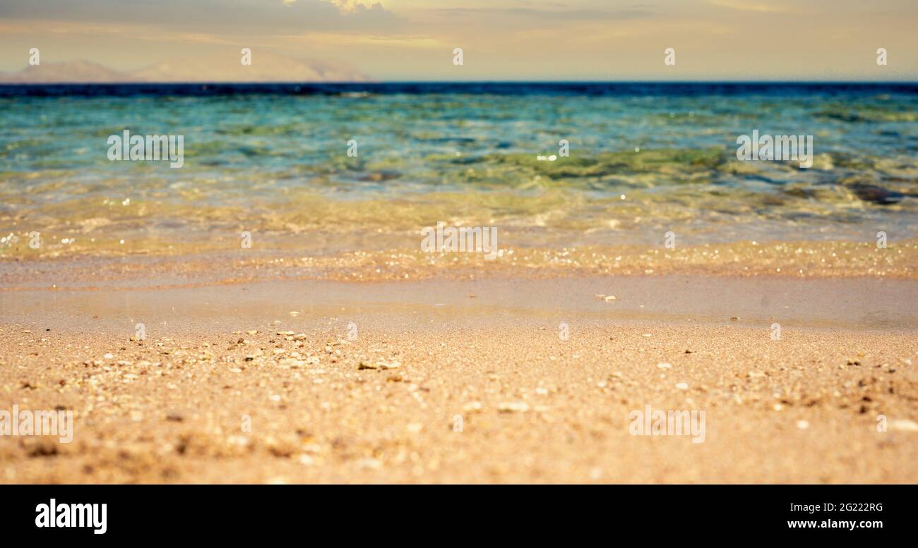 Isola tropicale paradiso di vacanza. Spiaggia e mare tropicale. Primo piano onde morbide del mare sulla spiaggia di sabbia. Spiaggia di corallo e acqua blu in luce su Foto Stock