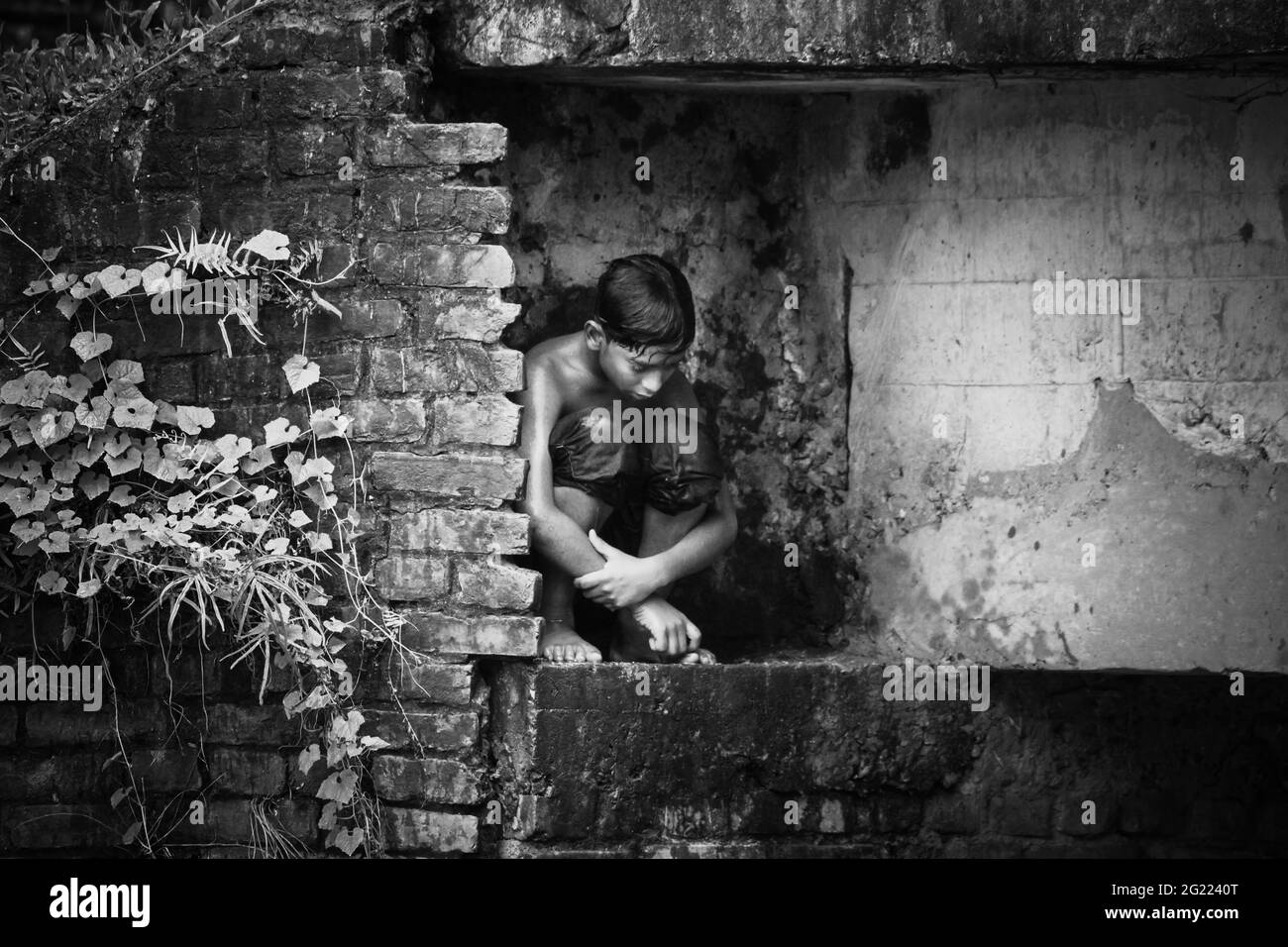Solo ragazzo seduto sotto il ponte Foto Stock
