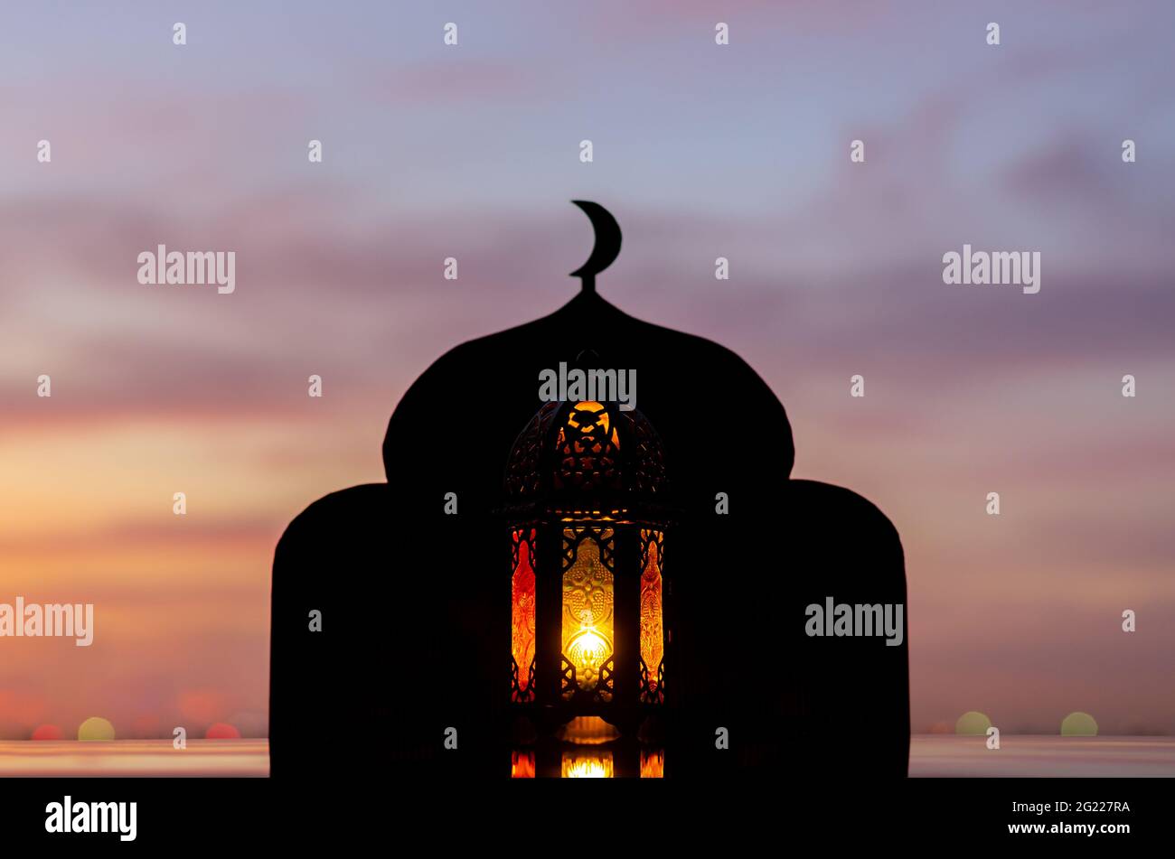 Lanterna con fuoco offuscato dello sfondo della moschea che hanno il simbolo della luna in cima e il cielo dell'alba. Foto Stock