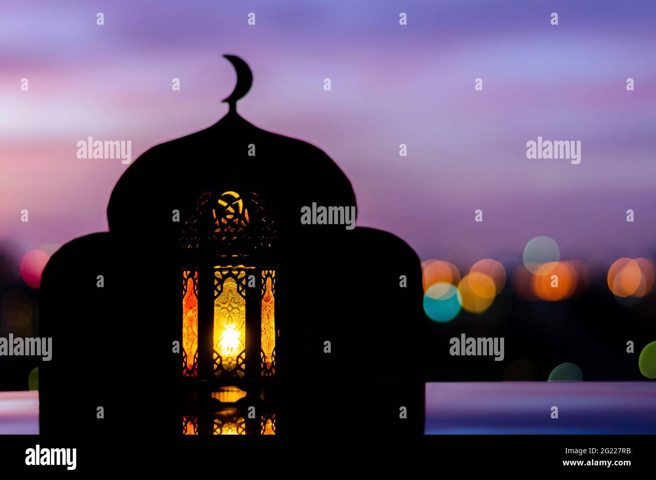 Lanterna con fuoco offuscato dello sfondo della moschea che hanno il simbolo della luna in cima e il cielo dell'alba. Foto Stock