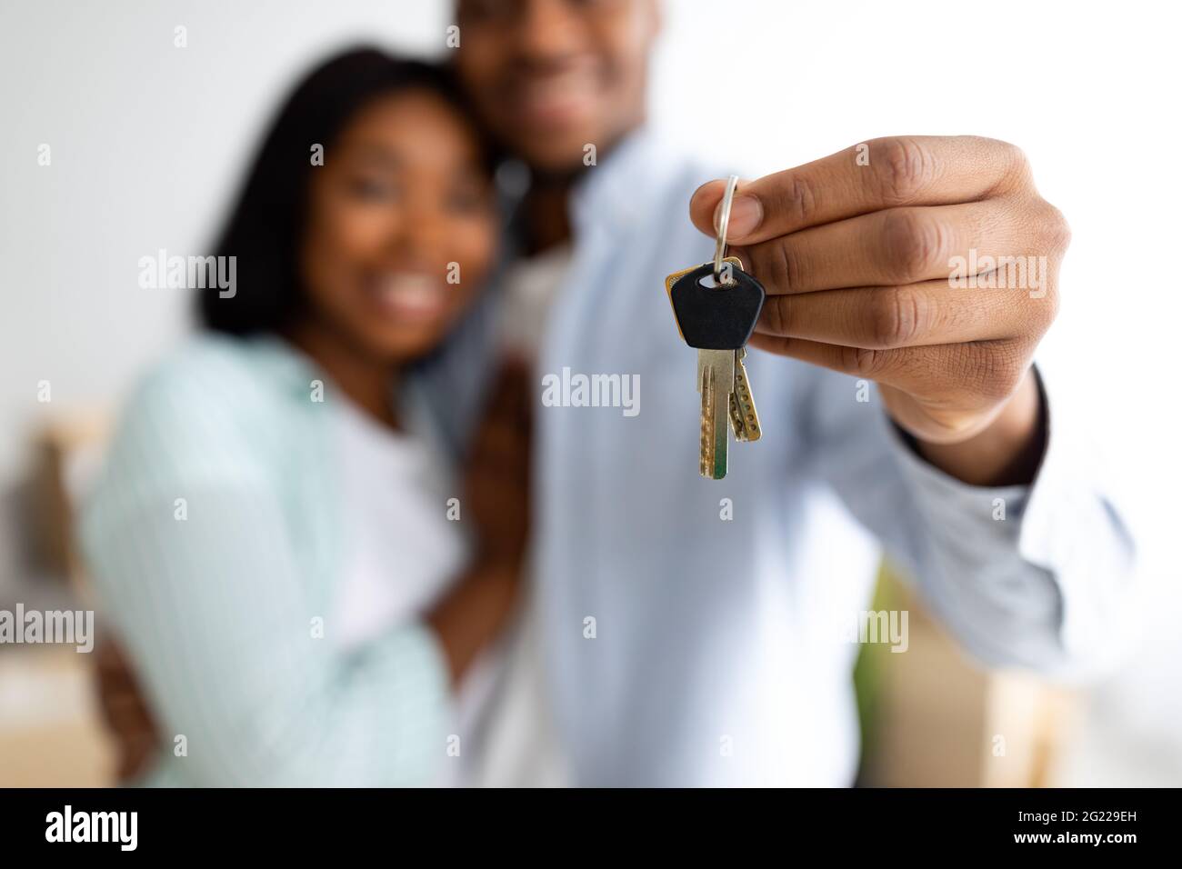 Nuovi proprietari di casa. Felice coppia afroamericana che tiene le chiavi di casa, celebrando l'acquisto del nuovo piatto, fuoco selettivo Foto Stock