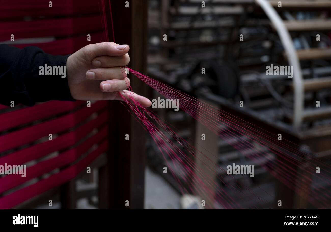 Primo piano di una lavoratrice che tiene filo d'oro, alla storica tessitura artigianale Luigi Bevilacqua, a Venezia, Italia Foto Stock