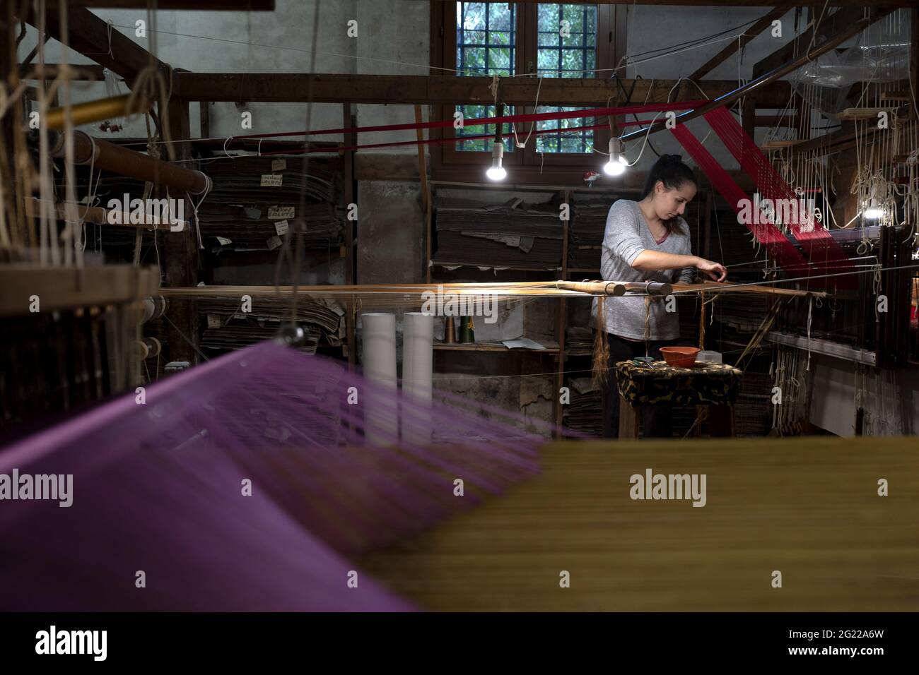 Lavoratrice della storica tessitura artigianale Luigi Bevilacqua, produce pregiati tessuti per mobili e alta moda, a Venezia Foto Stock