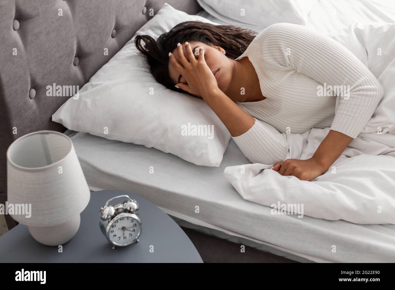 Donna afro-americana che soffre di insonnia coprendo il viso con palma Foto Stock