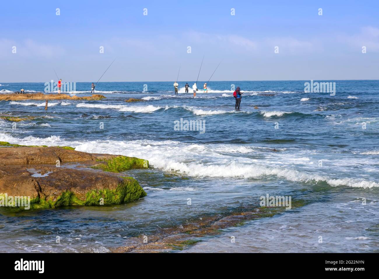 I pescatori pescano il pesce sulla costa mediterranea a bassa marea Foto Stock