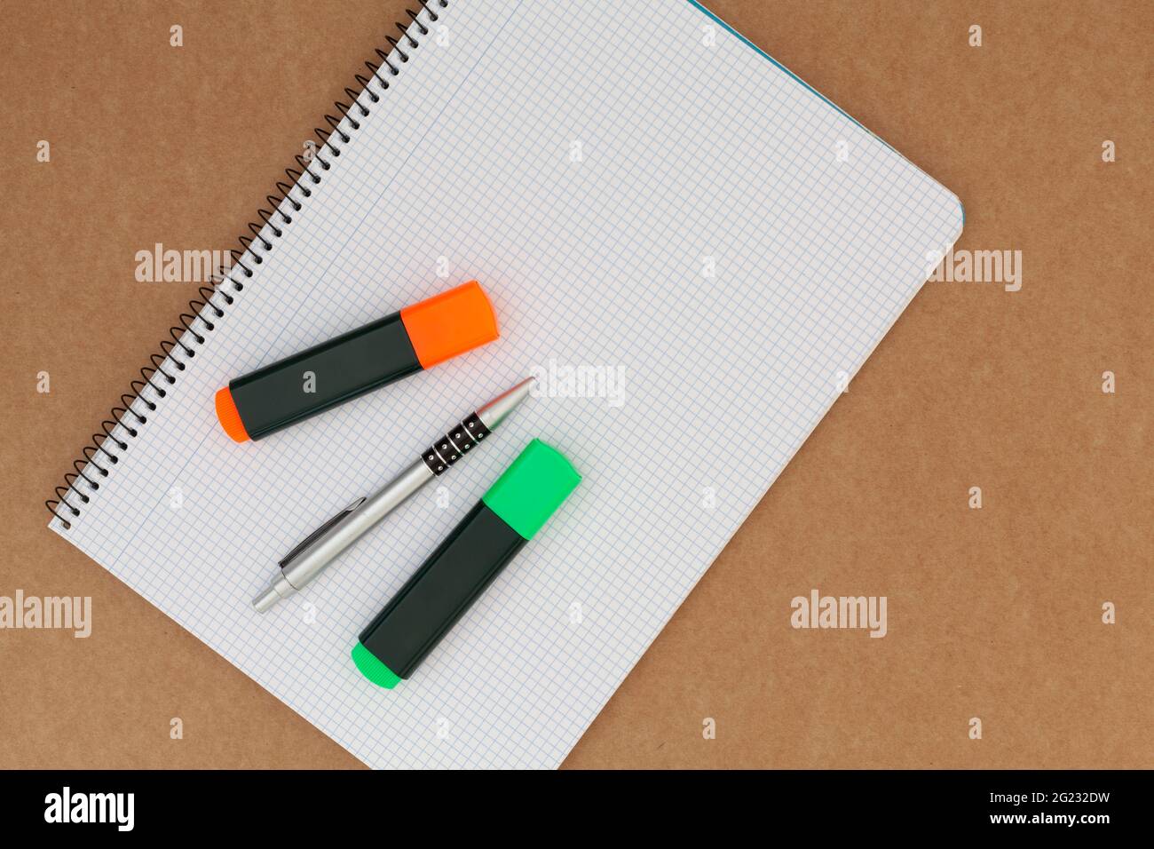 Notebook con fogli a griglia su cui sono presenti due pennarelli e una penna e che viene posizionato su una superficie di cartone. L'orientamento dell'immagine è orizzonte Foto Stock