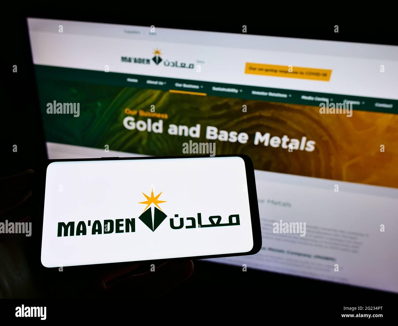 Persona che tiene il cellulare con il logo della società Saudi Arabian Mining Co. (Ma'ADEN) sullo schermo di fronte alla pagina web aziendale. Mettere a fuoco il display del telefono. Foto Stock