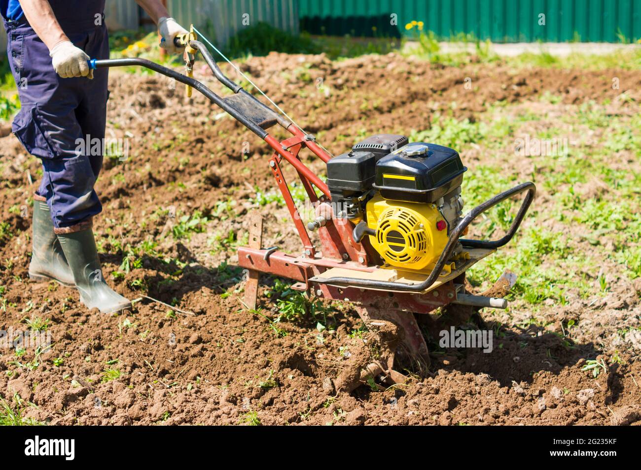 arando la terra nel giardino con un lavoro agricolo di cultivator. su arando il campo per semina semi. un uomo aratura la terra usando motocoltivatore Foto Stock