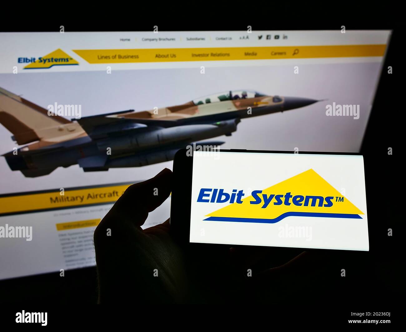 Persona che detiene il telefono cellulare con il logo della società di difesa israeliana Elbit Systems Ltd. Sullo schermo di fronte alla pagina web aziendale. Mettere a fuoco il display del telefono. Foto Stock