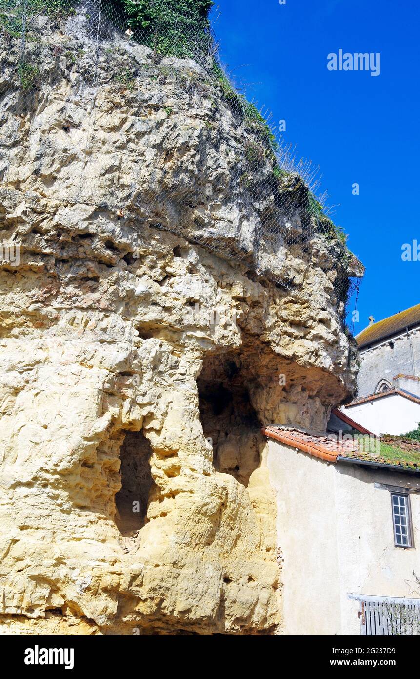 Piccola casa accoccolata sotto la scogliera sovrastante, parte della quale penetra la casa, sulla riva del fiume Gartempe a Montmorillon, Francia Foto Stock