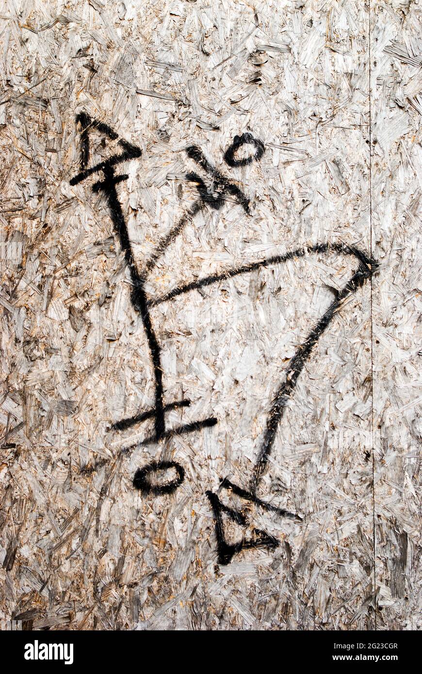 I graffiti che raffigurano un simbolo insolito che si muove in direzioni opposte spruzzano su una porta di legno. Foto Stock