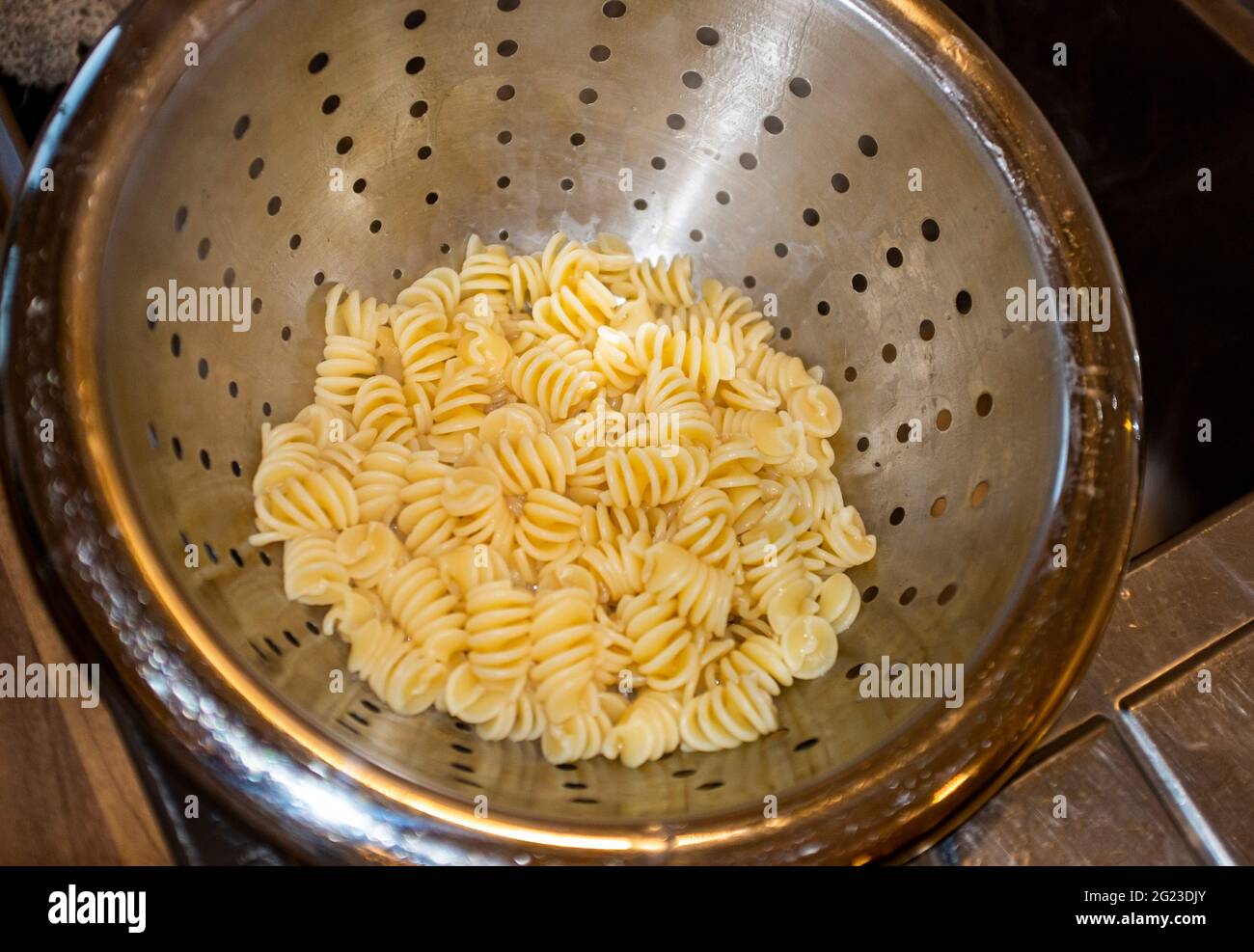 Cottura delle forme di pasta secca in acqua bollente e drenante Foto Stock