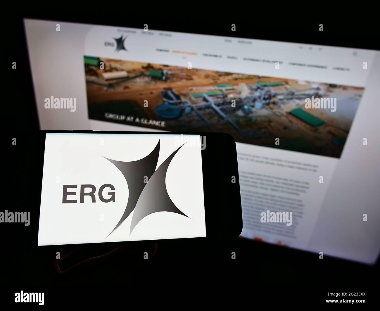 Titolare smartphone con logo della società mineraria Eurasian Resources Group (ERG) S.à r.l. su schermo davanti al sito. Mettere a fuoco il display del telefono. Foto Stock