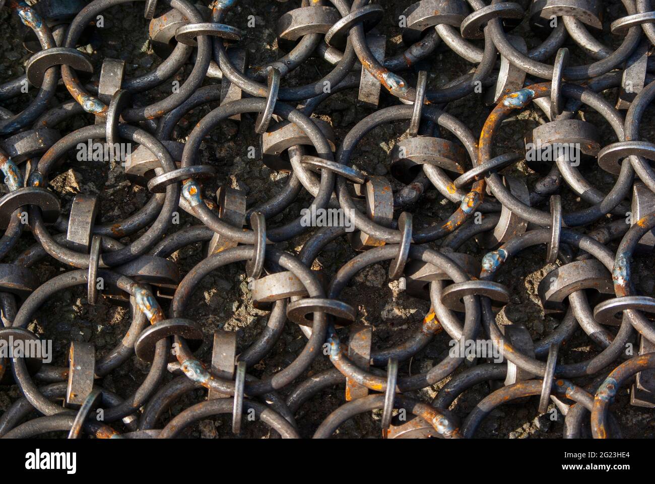 Un riassunto astratto di alcune catene da pesca metalliche circolari collegate sul porto. Foto Stock