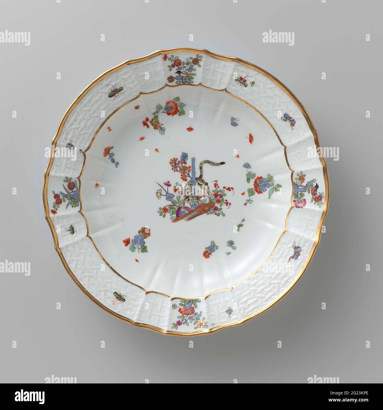 Tavola per zuppe, dipinta in modo multiplo con un decor kakiemon. Zuppa di porcellana dipinta. La piastra ha un bordo rigato e scalettato. La piastra è dipinta con una tigre, che ruota tra i fiori intorno a un gambo di bambù, blums Indiani sparsi, farfalle e rami con uccelli. Il bordo è decorato con il motivo 'Altbrandenstein'. La piastra è stata contrassegnata. Foto Stock