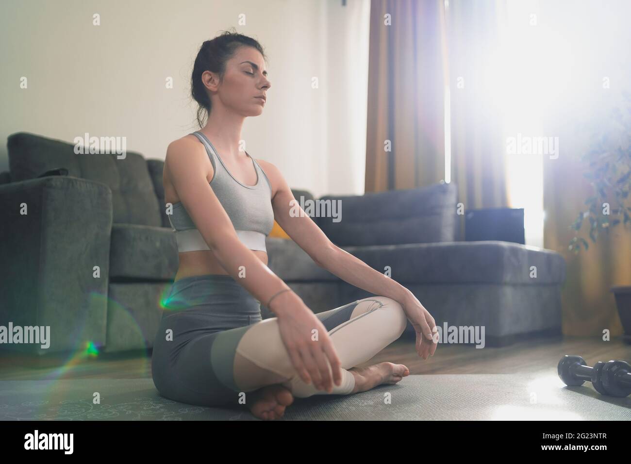 Calma donna seduta in lotus pongono la pratica di meditazione a casa Foto Stock